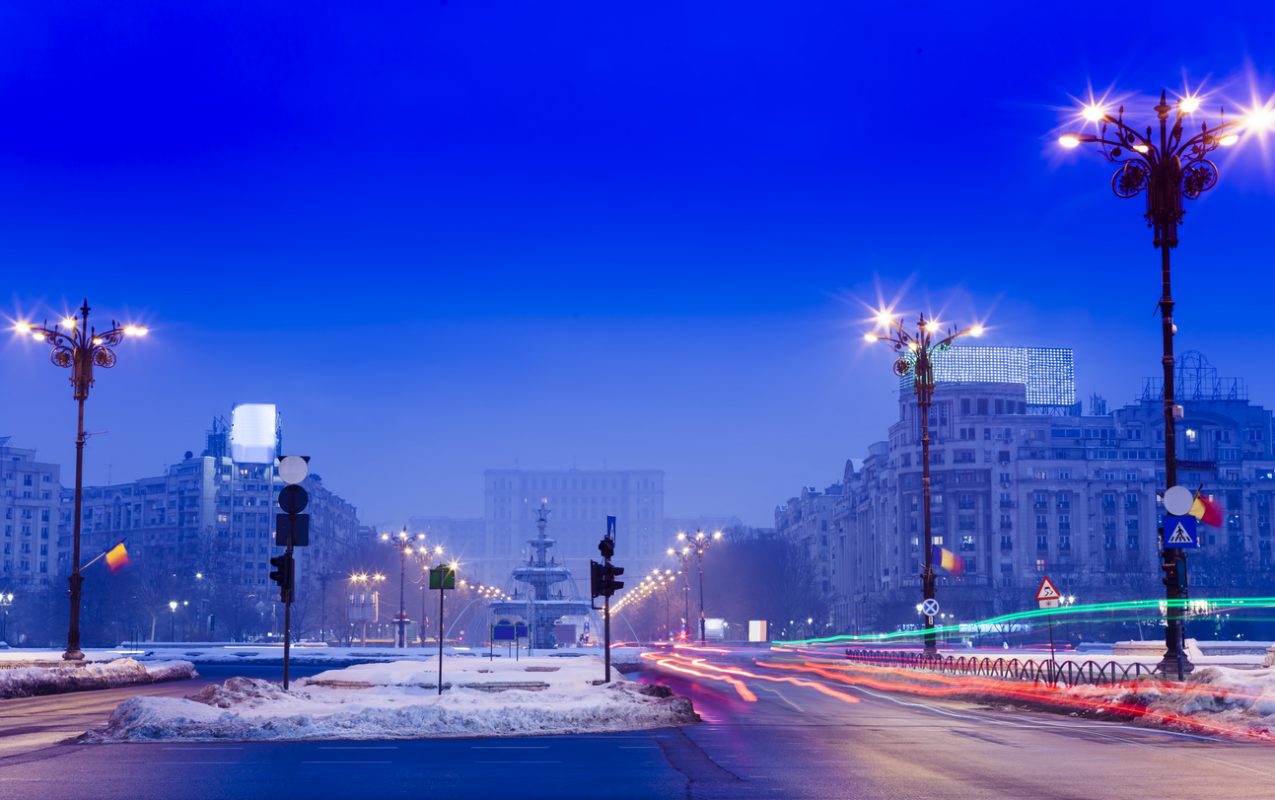Bucharest city architecture at night. There is snow on the ground and streetlights. This is a great view of Bucharest in winter