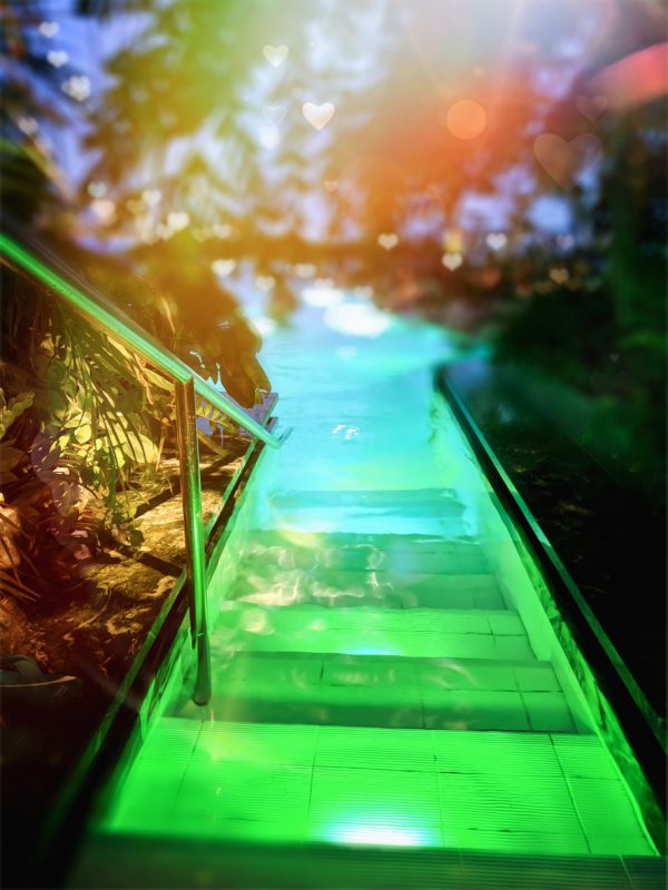 Grand entrance to the swimming pool on steps illuminated in green and in the distance blurred