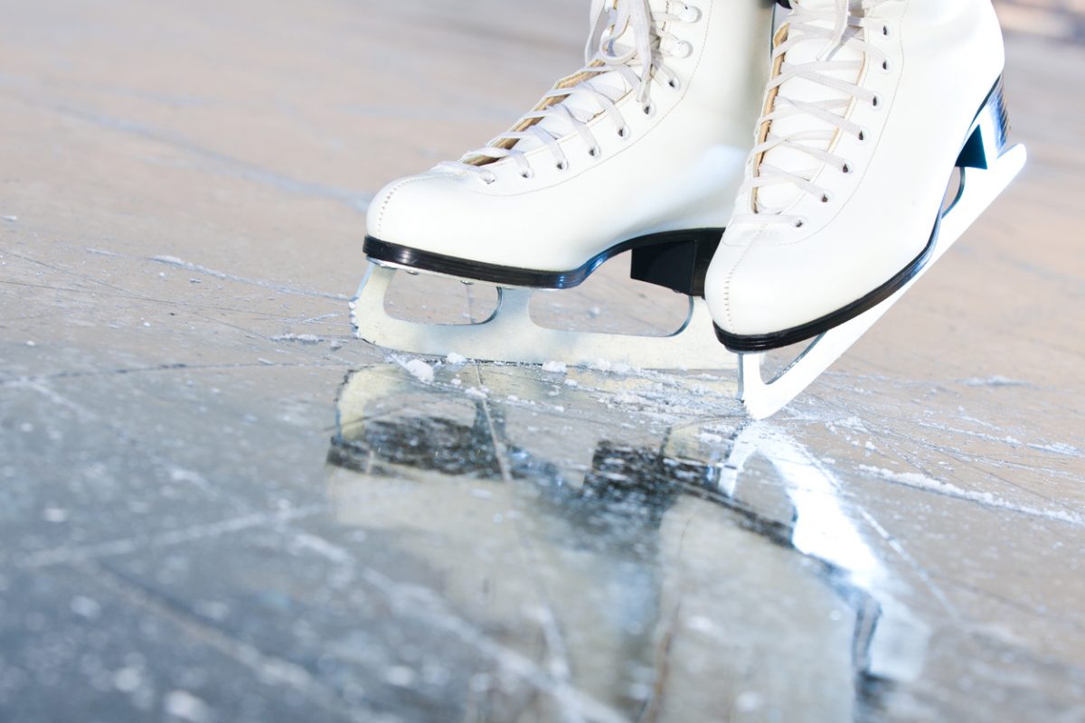 White ice skates with a reflection in the ice