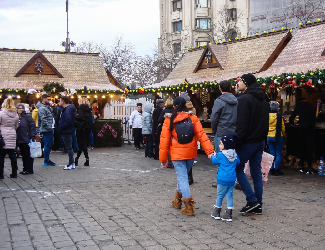 Decorated huge Christmas tree, lights, decorations, hot wine, hot chocolate, presents and people wandering at the Christmas market in Bucharest, Romania, 2019