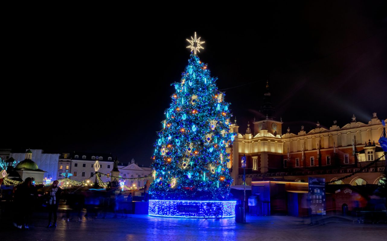 Krakow, Poland - November 29, 2019: Christmas tree on the old town market square in Krakow, Poland. Shining festive Christmas markets. Night panorama of old city decorated with bulbs