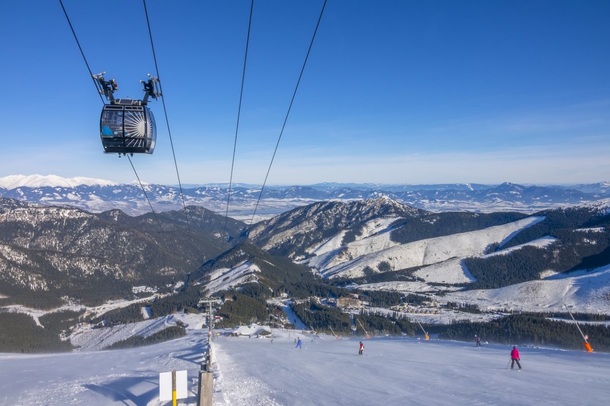 Slovakia. Winter ski resort Jasna. Sunny weather and blue sky over the ski slope. Ski lift and panorama of snow-capped mountain peaks on the horizon