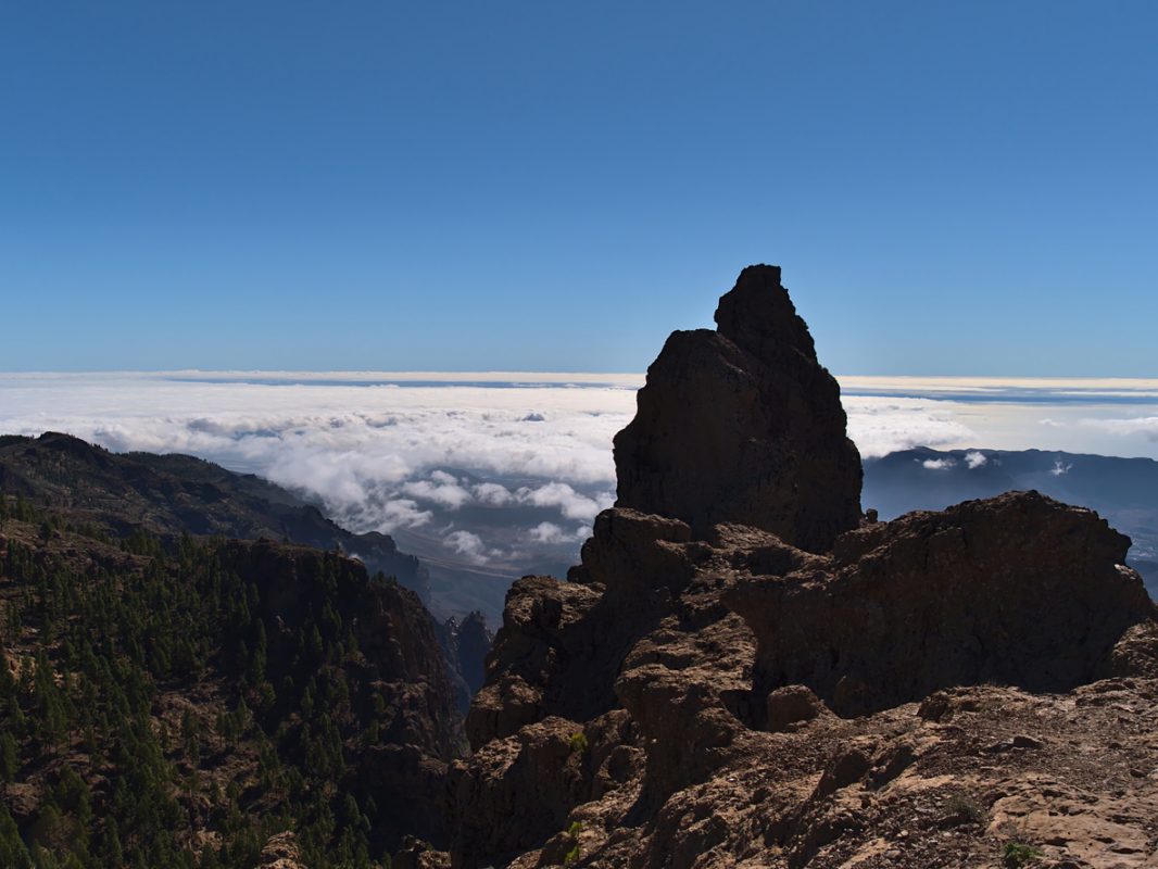 Beautiful view of rock Morro de la Agujereada (1,956 m), the highest peak of island Gran Canaria, Spain, located in the mountains near Pico de las Nieves on sunny day above a sea of clouds.