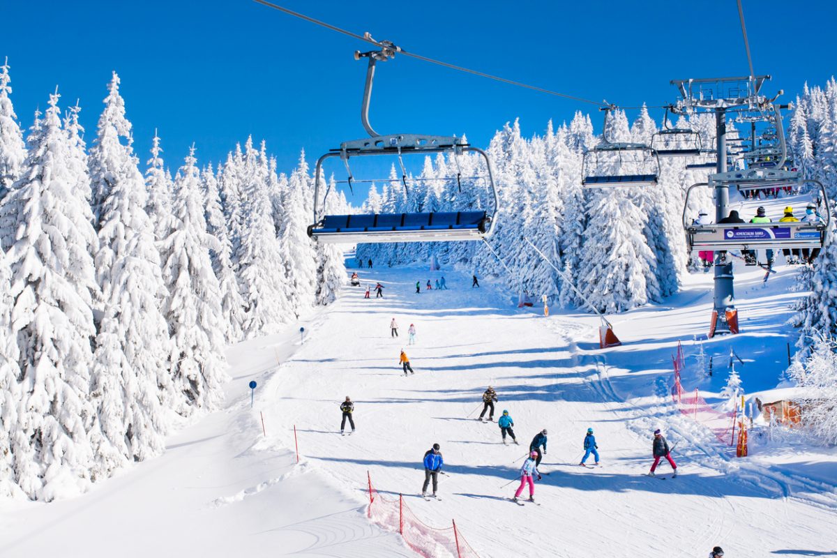 Kopaonik, Serbia - January 19, 2016: Ski resort Kopaonik, Serbia, ski slope, people on the ski lift, skiers on the piste among white snow pine trees forest
