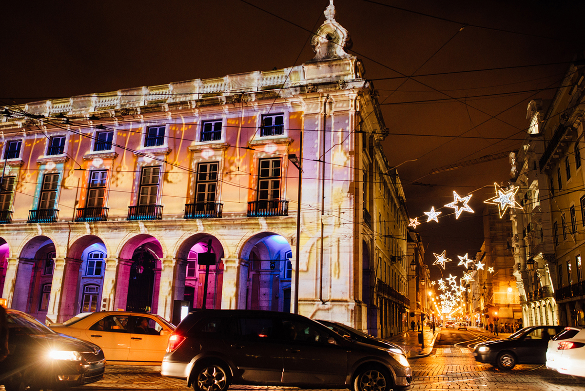 Traffic during festive Christmas time in Lisbon, Portugal. Cars on the street decorated with illumination, building lit with electric lights on background. Night photo