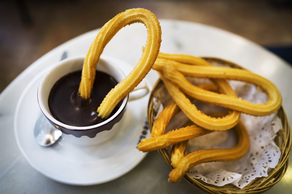 This image captures shows tradition and delicious fresh churros along side hot chocolate at a cafe in Spain.