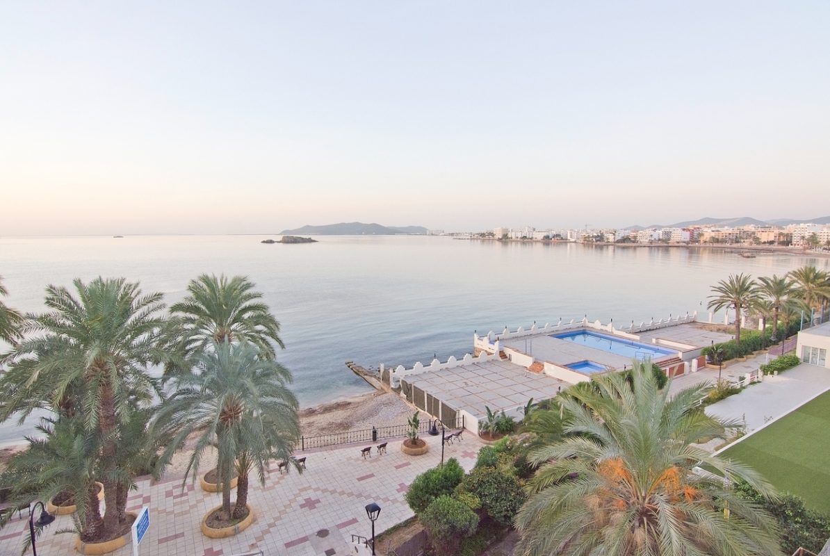Ibiza, Balearic islands, Spain - December 16, 2015: Figuereta bay in bright sunshine with seaside hotels, palms and swimming pool on a bright winter morning in December.