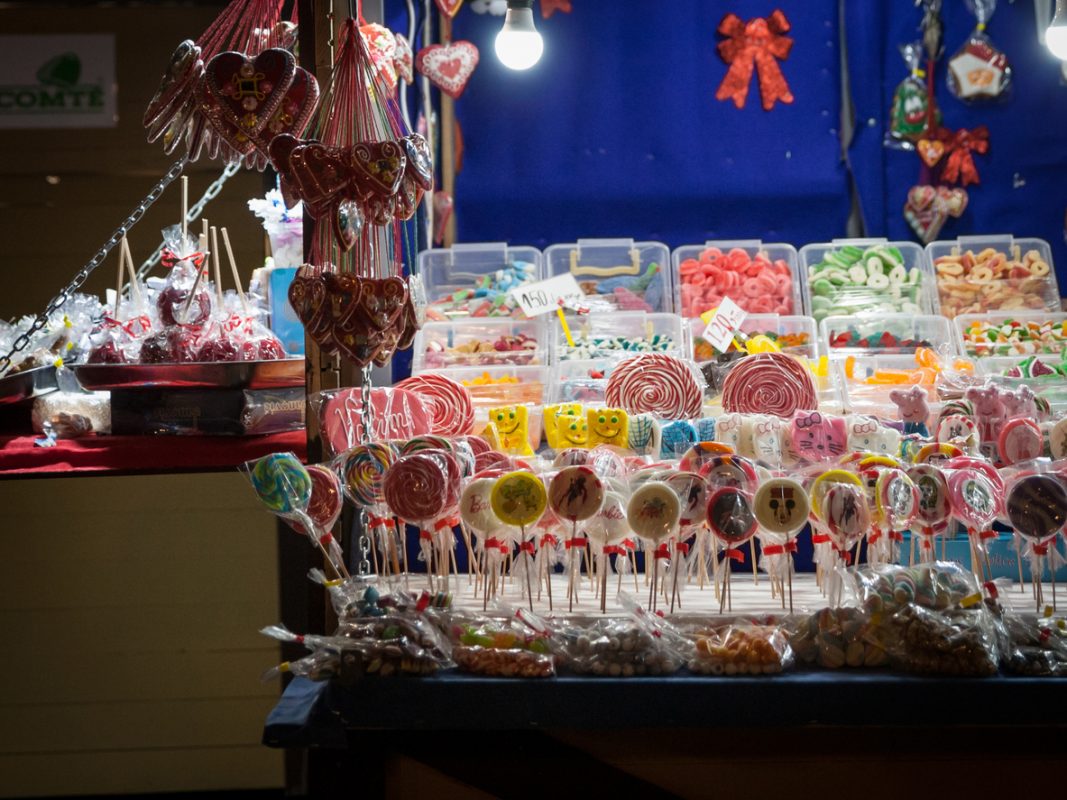Picture of the stalls of a candy christmas market displaying candies on loose, of various types, such as lollipops, gummy bears and other sugar variations