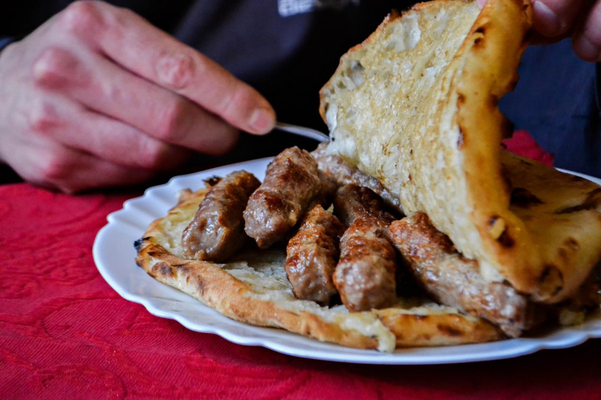 Closeup of traditional Balkan food- meat in bread/ man eating cevapi