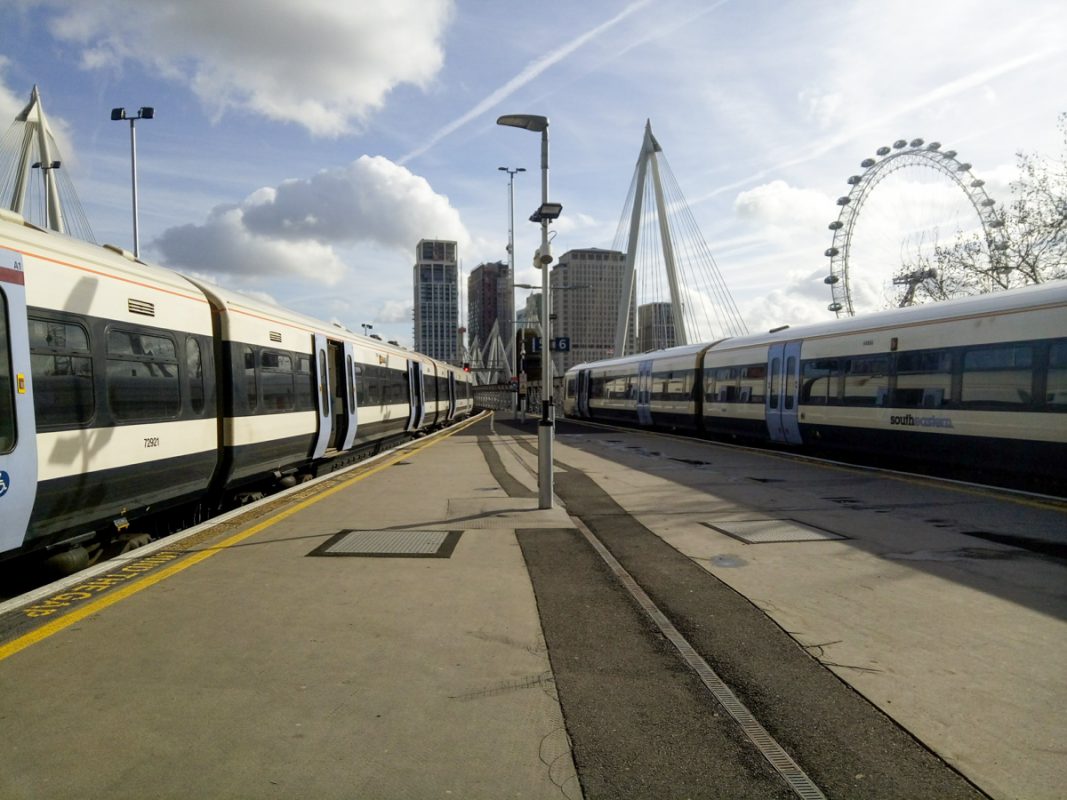 Two trains on each platform at Waterloo East station with the London Eye in the background.