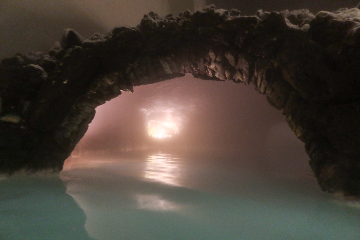 An archway over the azure water of the blue lagoon in Iceland, with warm water steaming upwards. 