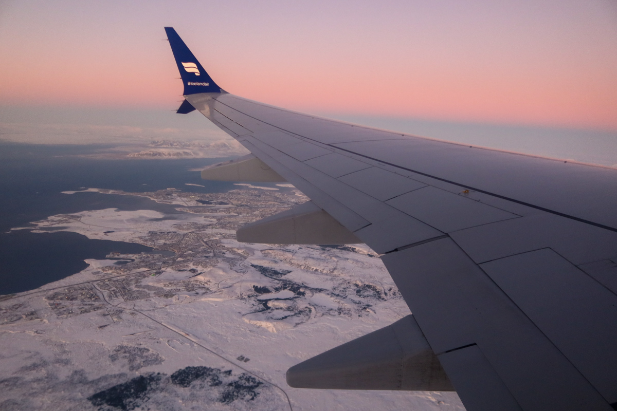 IcelandAir wing of a plane landing into the frozen country as the sun sets.
