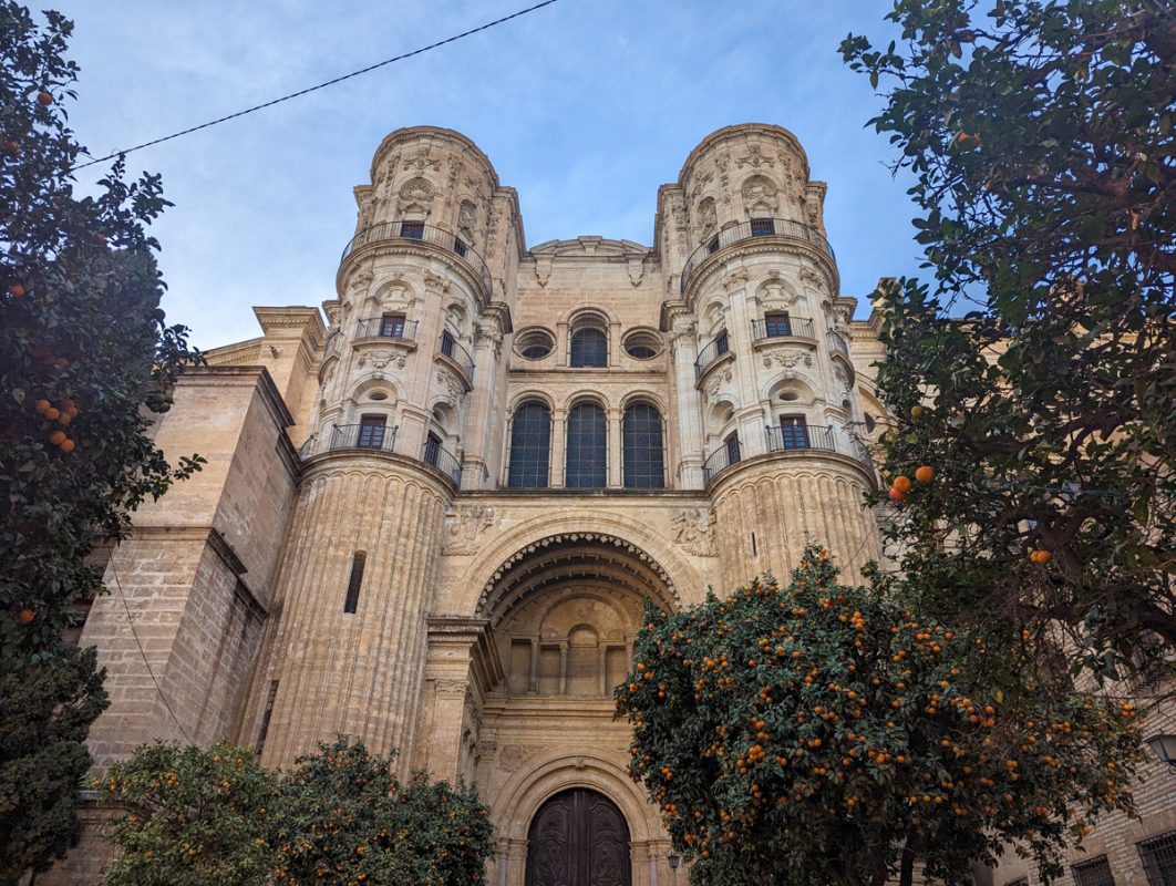The back of Malaga Cathedral, with trees with oranges in the foreground.