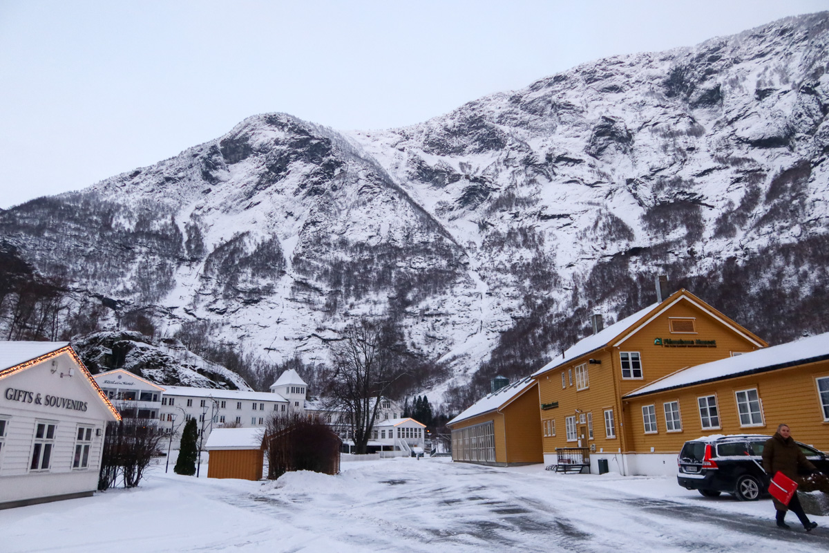 The wooden houses of Flam with snow covered mountains in the background.