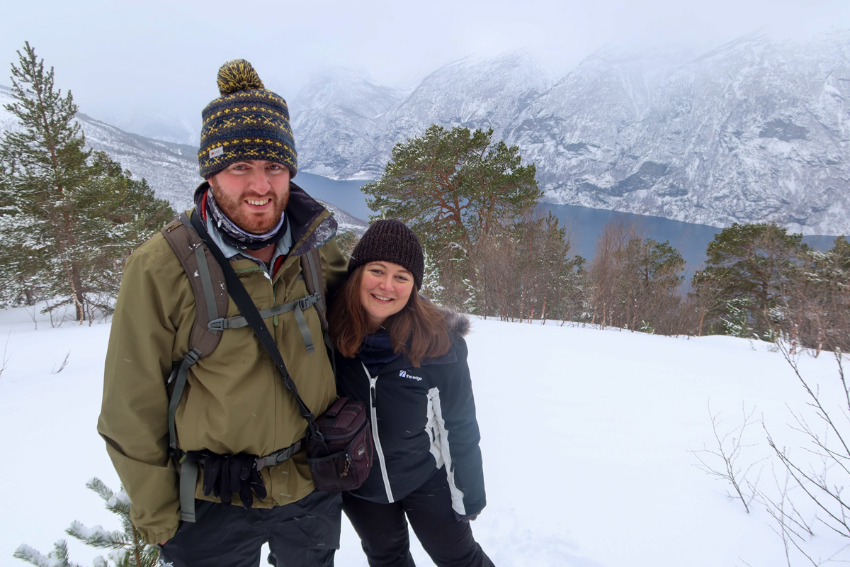 Claire and Richard snowshoeing in Norway, with a view of the fjord in the background.