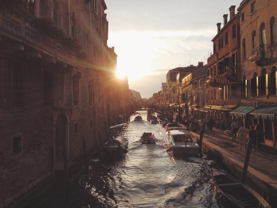 Sunset over a canal of Venice with buidlings on either side