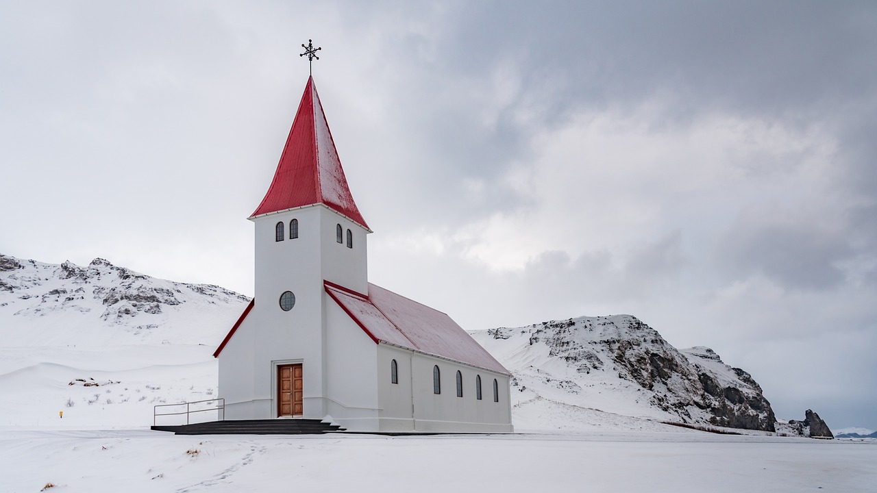 A church with a red roof in the snowy landscape of Vik