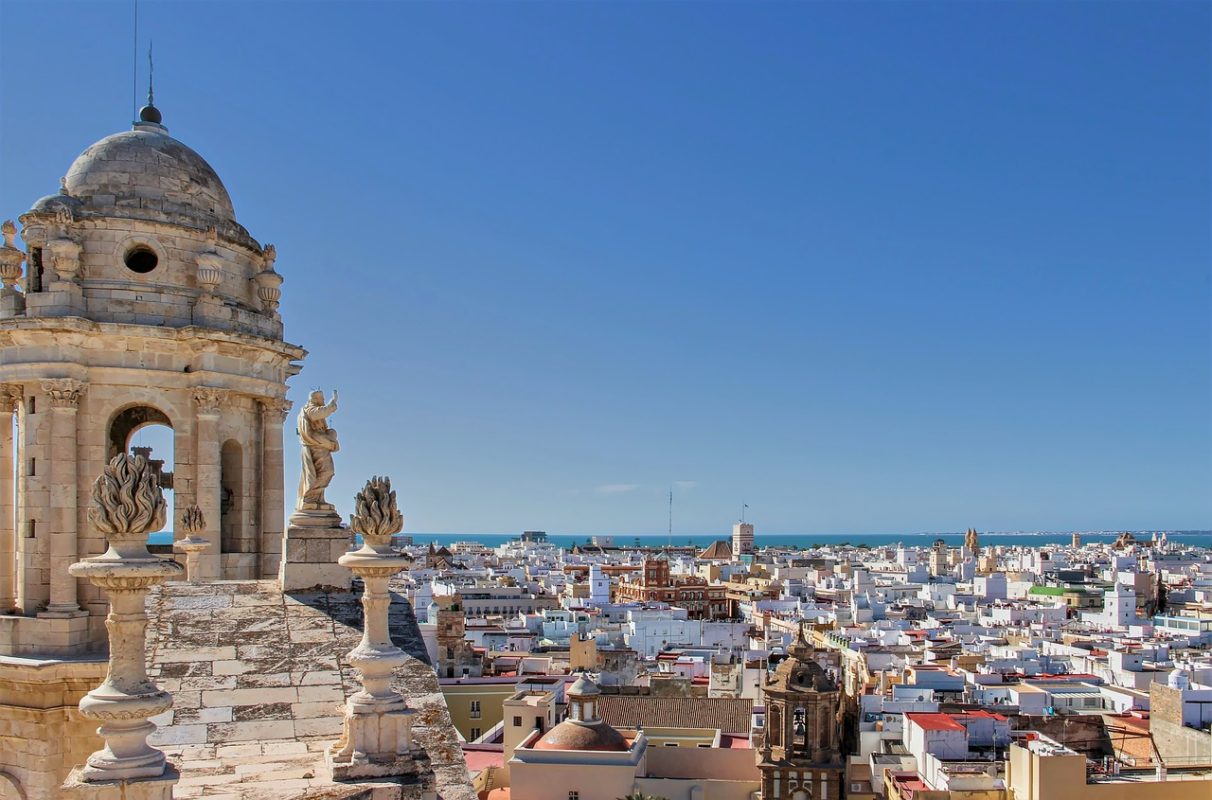 Historic buildings in Cadiz, spread out in a panorama, with blue sea and sky in the background.