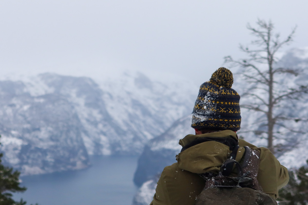 back of a man's head wearing a woolly hat looking over the fjords near Flam, NOrway.