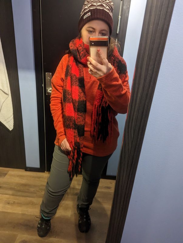 Girl standing infront of a mirror wearing a jumper, scarf and wooly hat