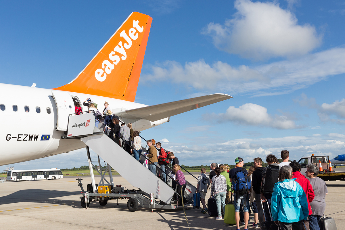 BRISTOL, UK - JULY 11, 2016: A queue of passengers boarding the tail end of an Easyjet aircraft at Bristol Airport on a bright sunny day.