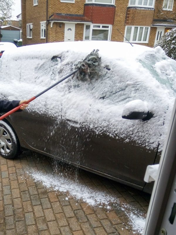 Mum clearing snow off her car in England. 
