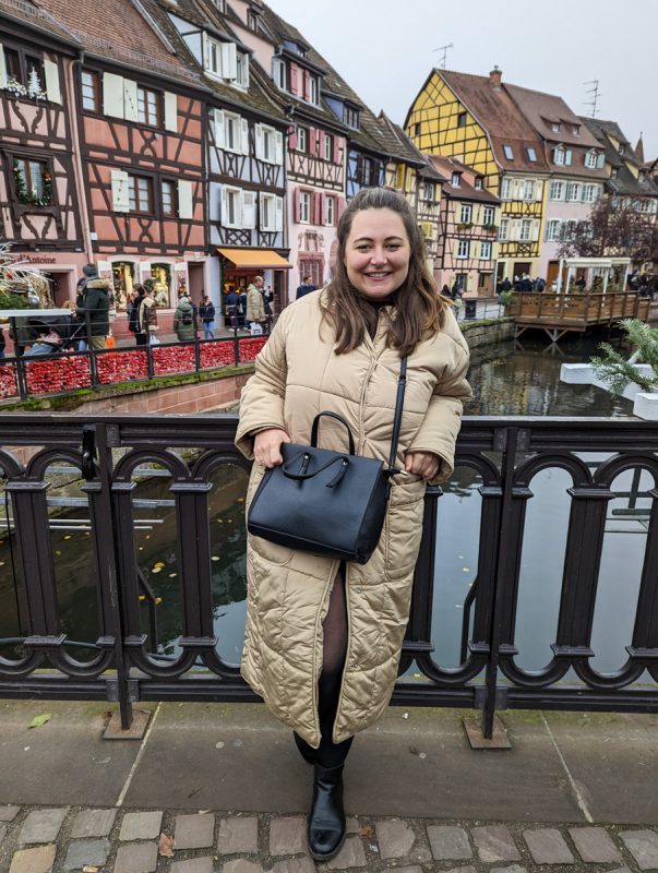 Claire wrapped up in a coat on a bridge in Colmar. 