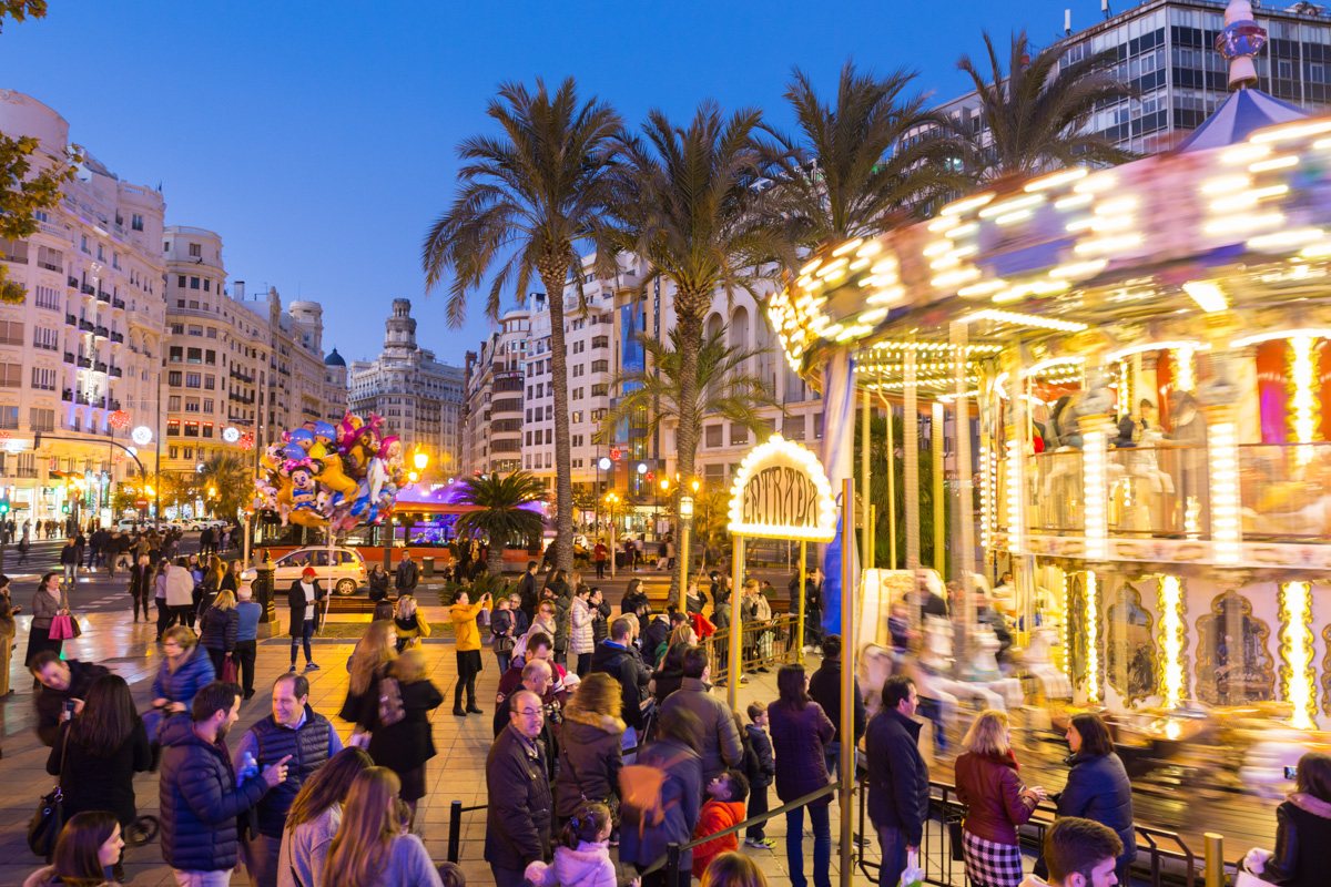 Valencia, Spain - Dec 16, 2017: People having fun in christmas spirit on Christmas fair with carousel on Modernisme plaza of the city hall of Valencia on 16th of December, 2017 in Valencia, Spain.