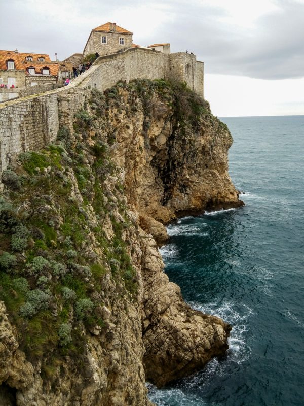 Rocky cliff with Dubrovnik walls and buildings on the top.