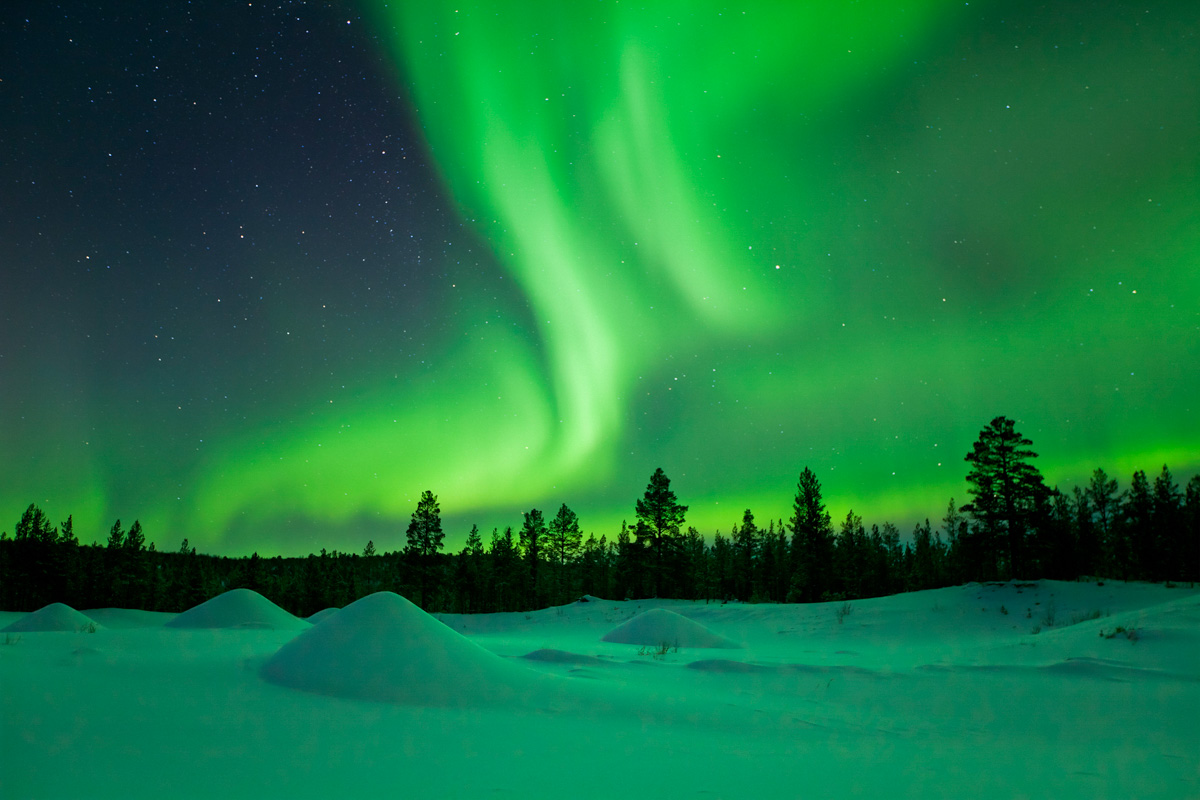 Spectacular aurora borealis (northern lights) over a snowy winter landscape in Finnish Lapland.