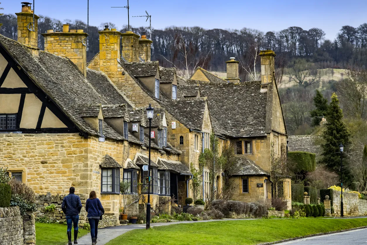 February 19th. 2017 Broadway Village, Cotswolds, Worcestershire, Midlands, England, UK. This is the High Street in the famous and much visited tourist Costwolds village of Broadway. The road is lined on either side with honey coloured limestone buildings, traditional to the area. It is a bright warm afternoon in late winter. There are tourists and visitors in the picture.