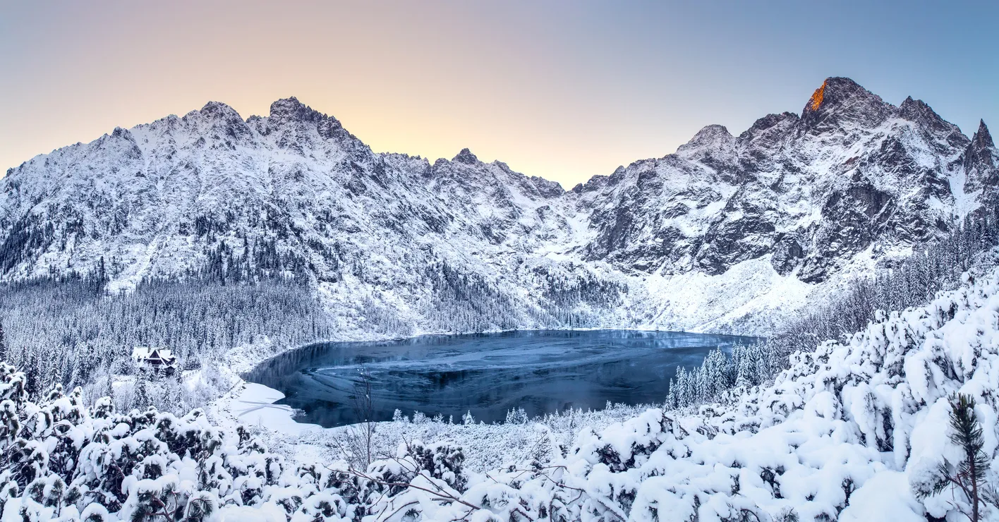 Winter dawn in mountains. Beautiful winter landscape with mountain lake and snowy hills. Morskie oko lake. Lake in tatra mountains in winter at dawn. Poland, Zakopane.