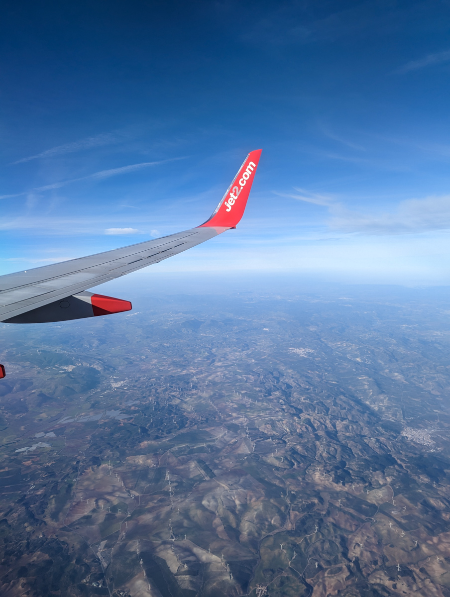 Wing of Jet2 plane on the way to Malaga in winter with mountains in the background