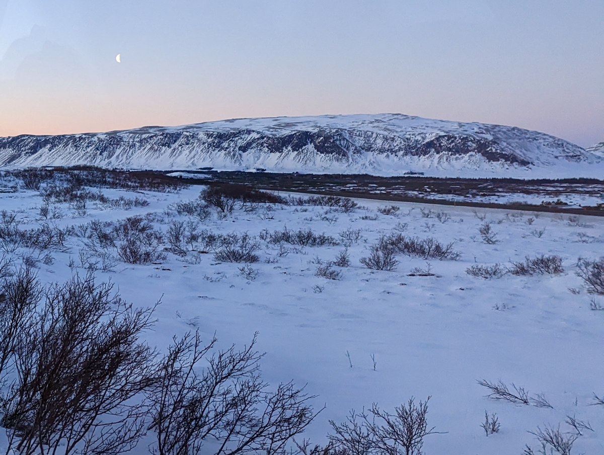 The rocky landscape of the golden circle, covered in snow with a hill in the background.