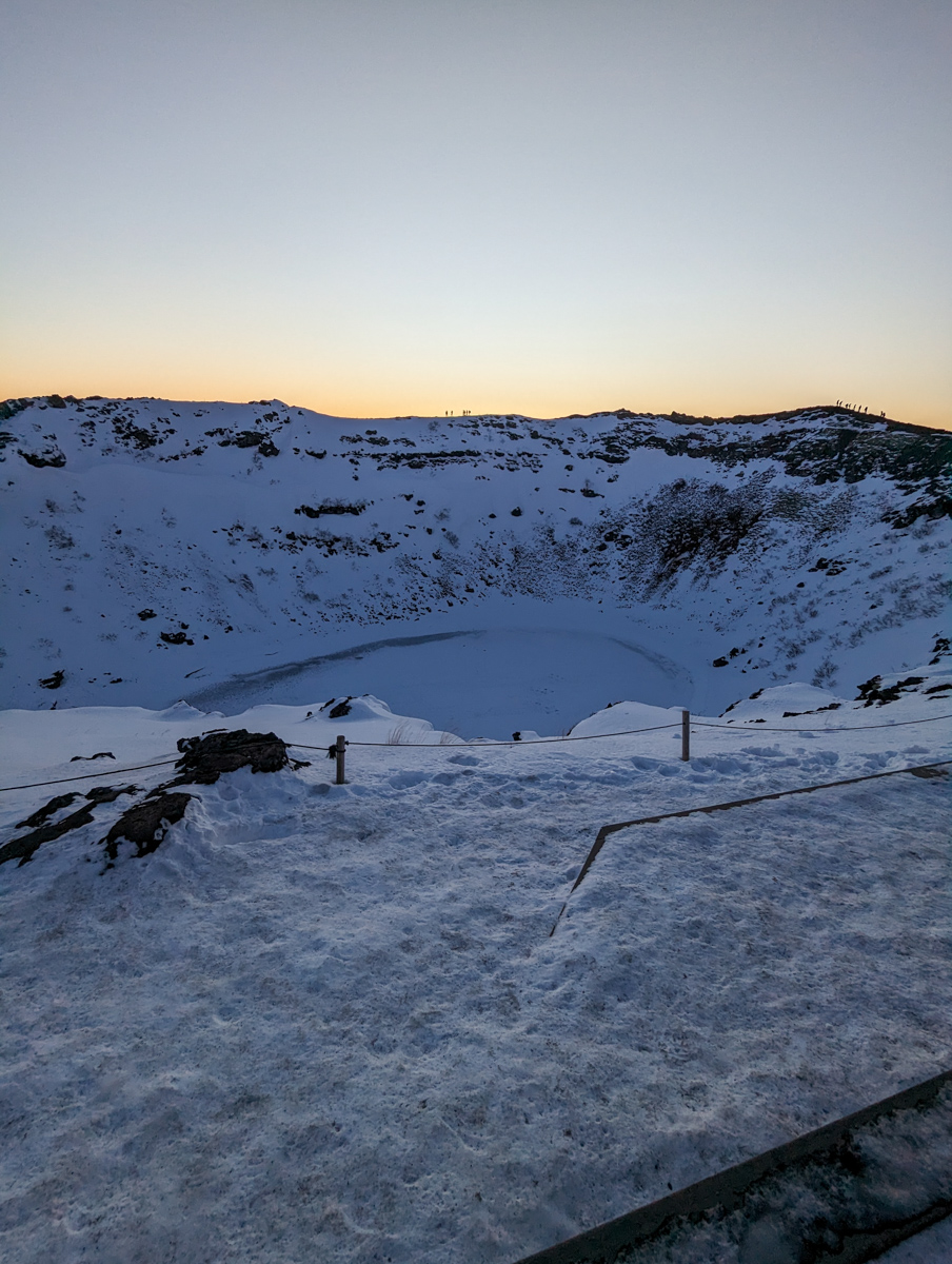 Portrait photo of the frozen Kerid Crater, a snow-covered landscape.