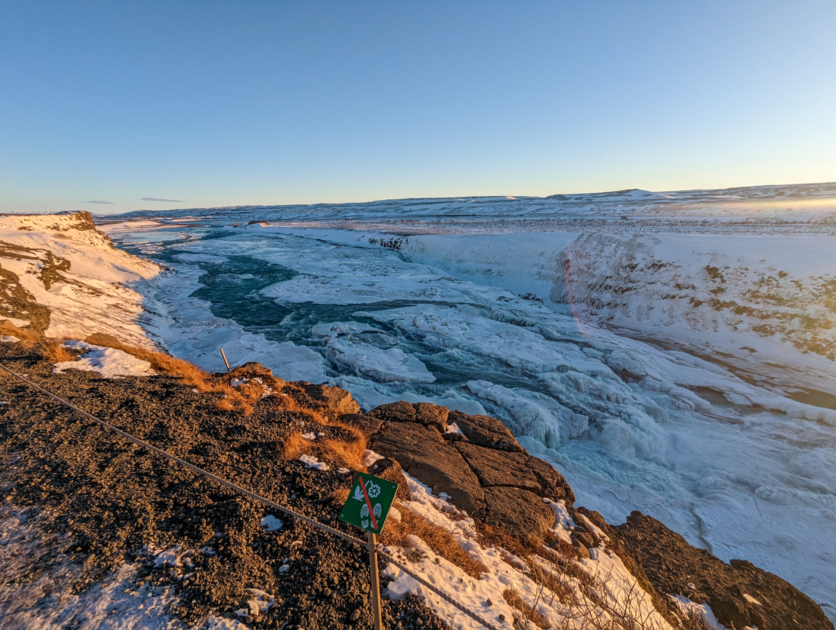 View over Gullfoss Waterfall, a beautiful waterfall that you can view from above in winter. The landscape is snow covered and sun has just risen.