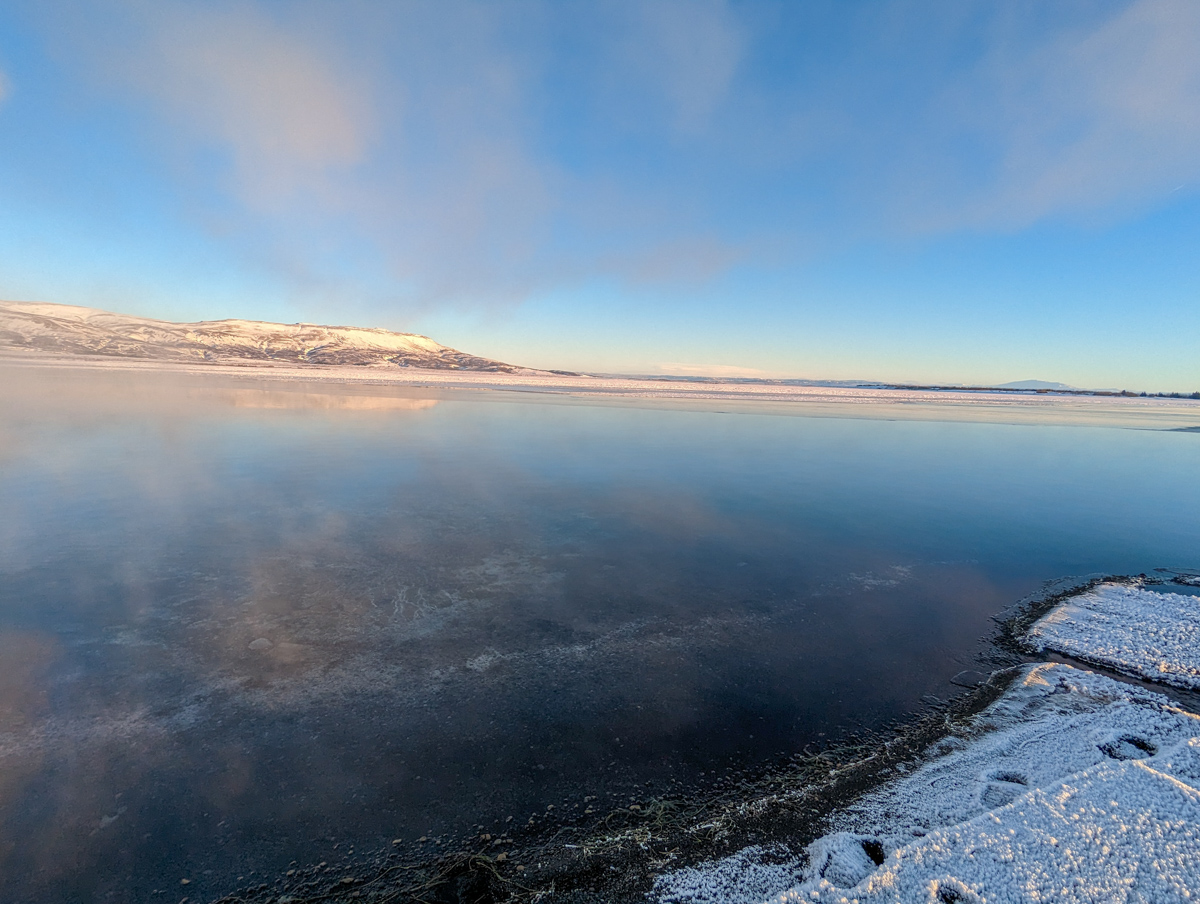Laugarvatin Fontana, thermal waters where bread is baked. Steam rises off the hot pool and snow lines the edge.