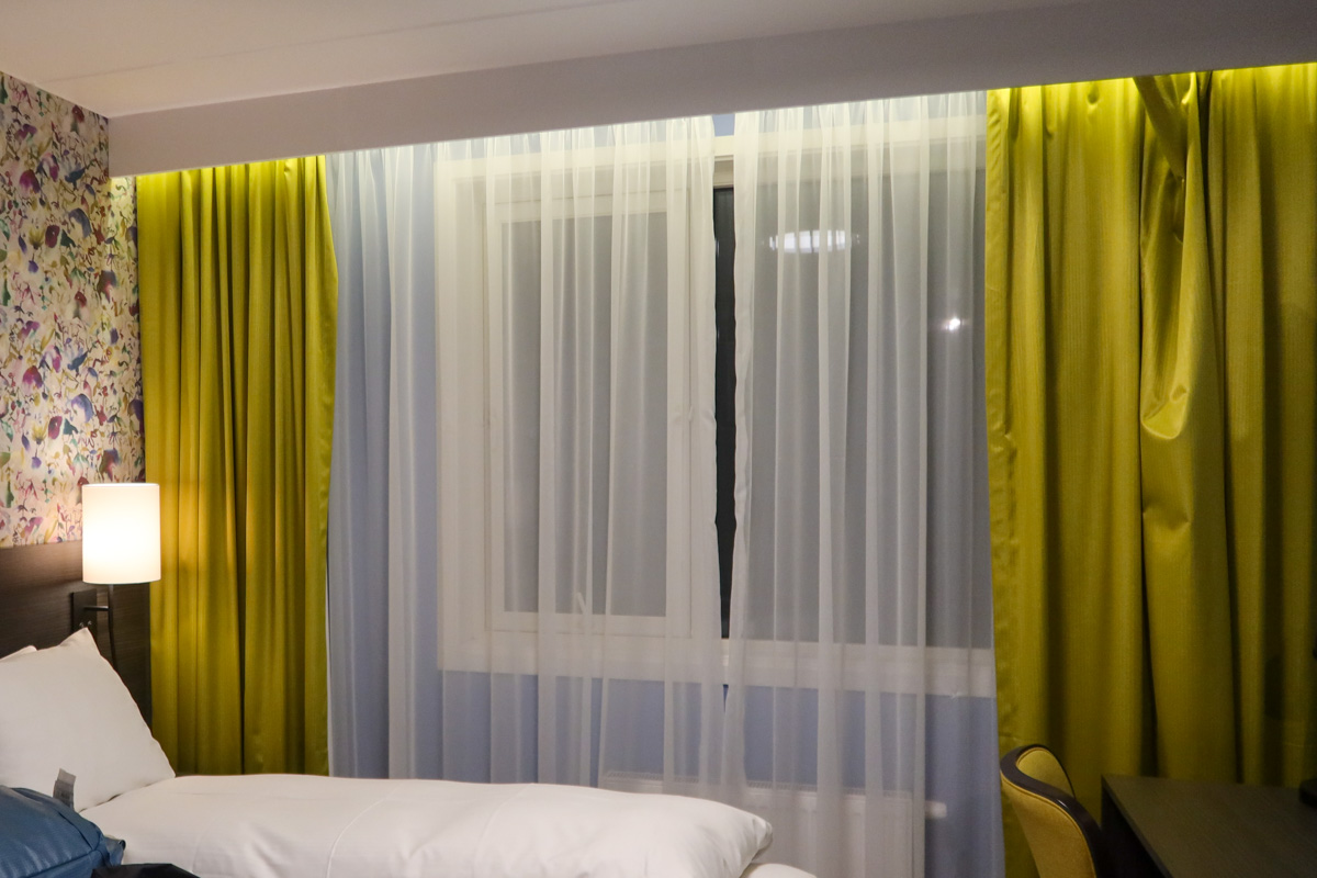 Bed at Thon hotel Tromso, with green curtains and floral wallpaper