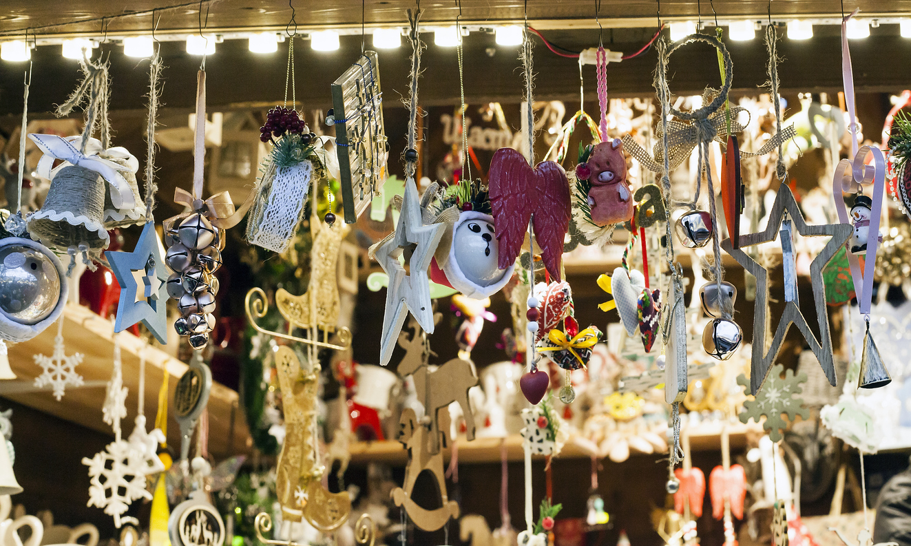 Small wooden handmade toys selling at Xmas Fair. Christmas market with traditional decorations close up. Holidays kiosk with festive gifts and souvenirs at city street