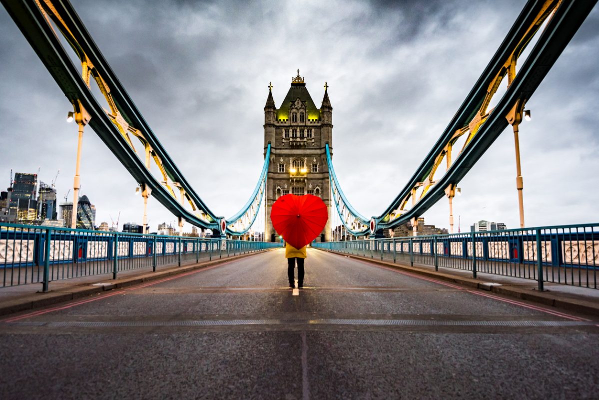 Girl with heart shaped umbrella on Tower Bridge, London without traffic.