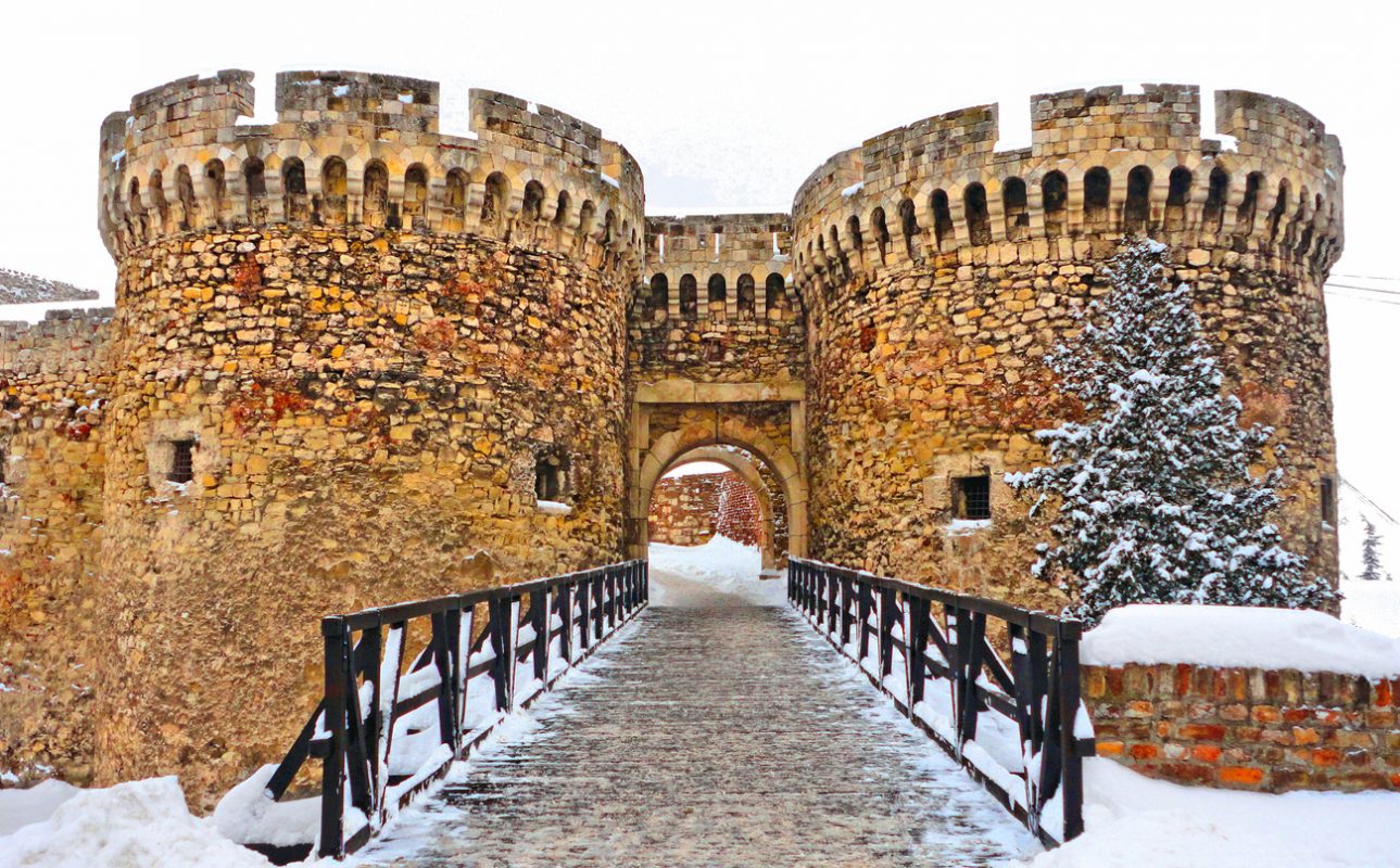 small wooden bridge and medieval gate with stone brick wall in Belgrade fortress under snow, Serbia