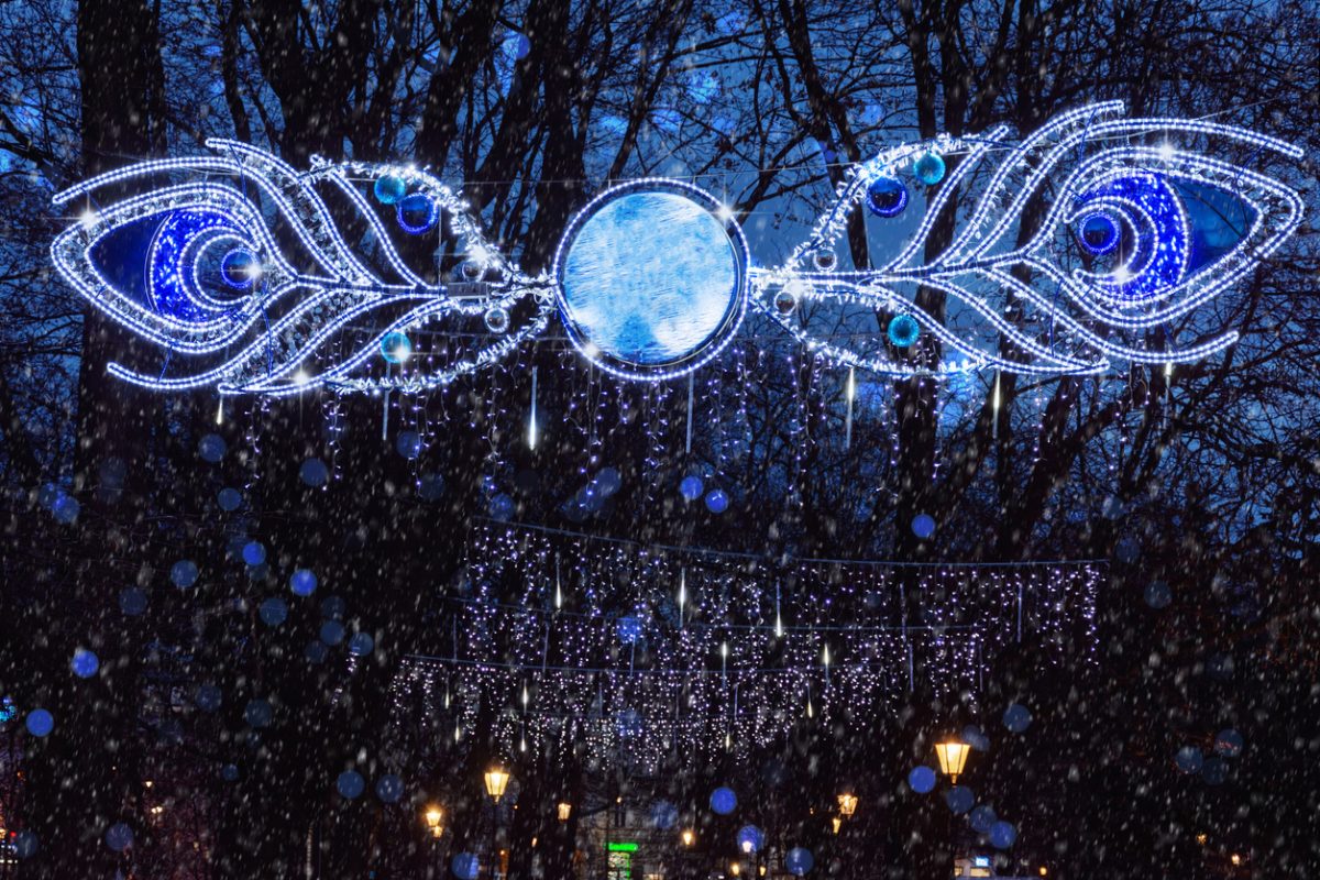 Blue Christmas illumination in city street in snowy night. Christmas decoration outdoors.