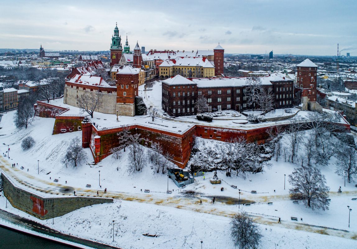 Krakow, Poland - January 14, 2021: Historic royal Wawel Castle and Cathedral in winter with white snow, walking people and promenade.