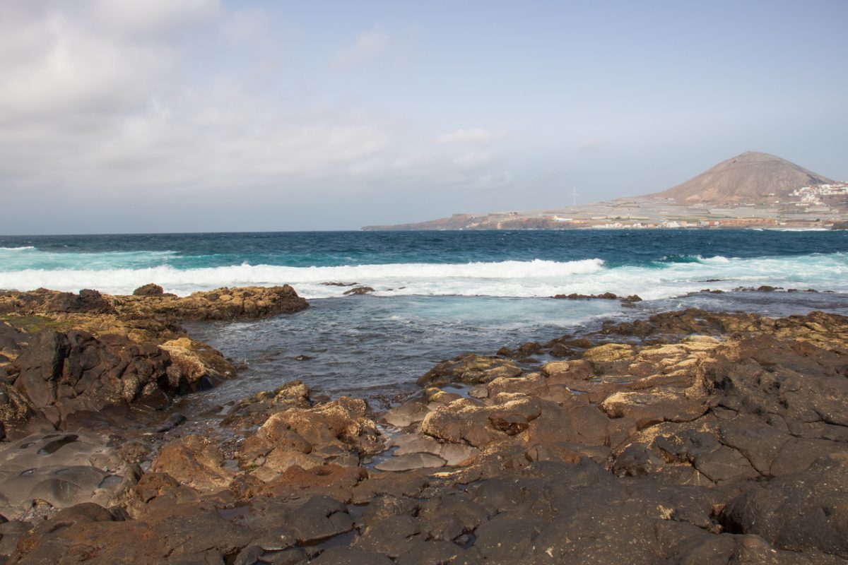 Coastal landscape in the north of Gran Canaria with the Gáldar mountain in the background. Rocky volcanic coast of the Canary Islands with swell of the Atlantic Ocean.