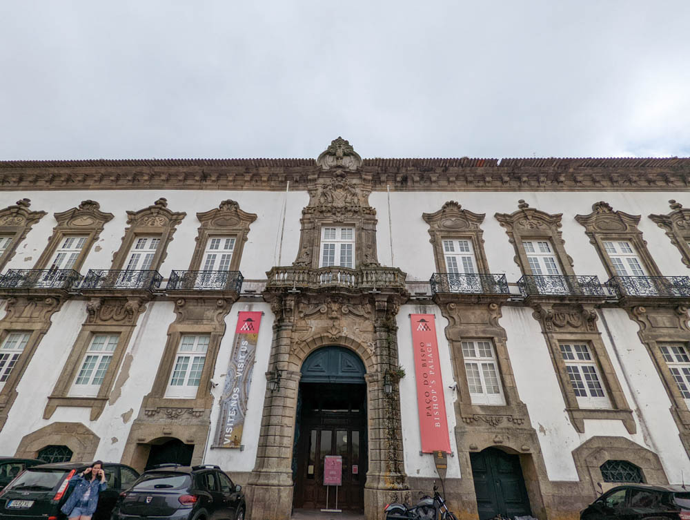 Face view of Bishop's Palace, near Porto Cathedral in Porto. The sky is grey and the architecture is white, in a Rocco style