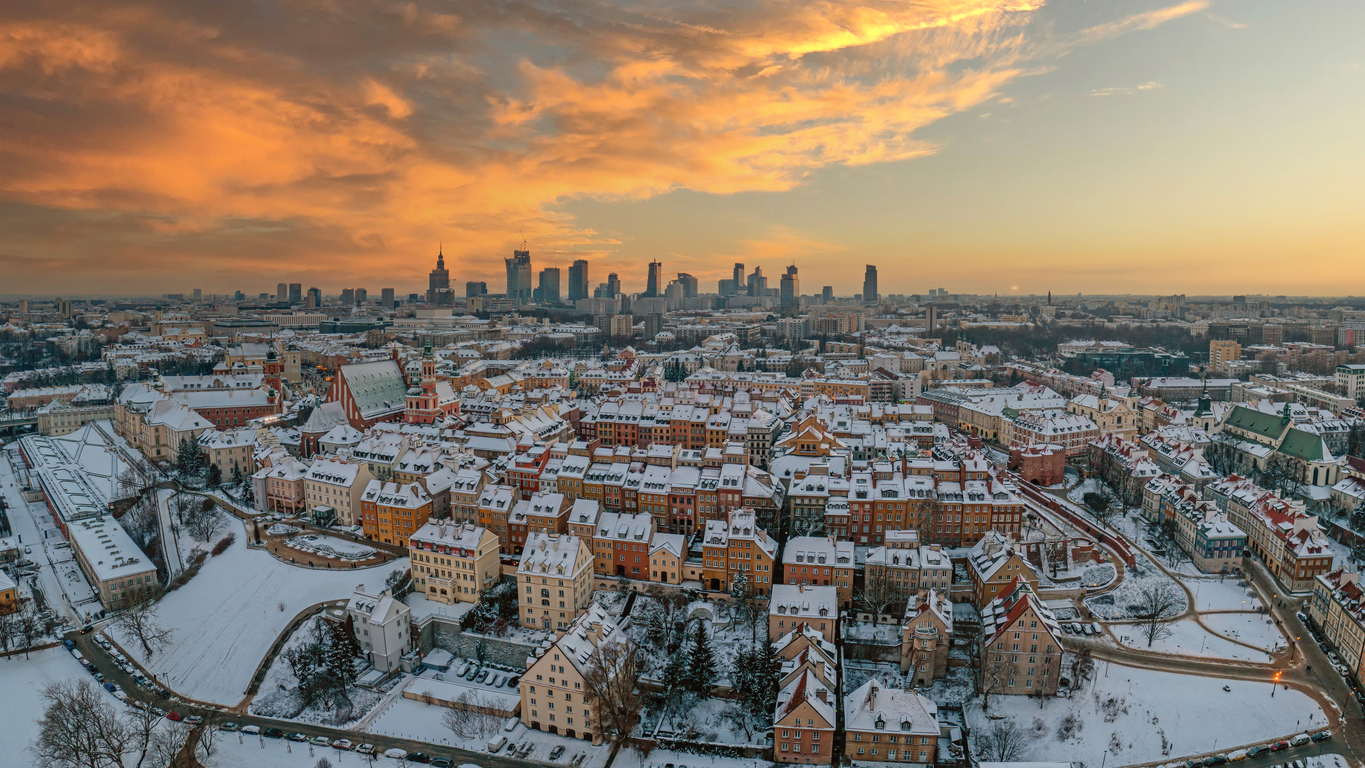 Warsaw old town, snow-covered roofs and and distant city center at dusk, aerial winter panorama