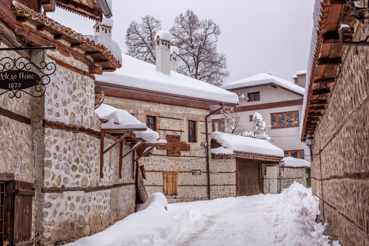 Bansko, Bulgaria - February 2, 2022: Old town snow winter street view, traditional houses in bulgarian ski resort