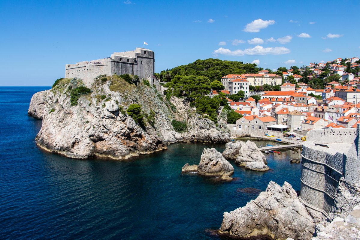 DUBROVNIK, CROATIA - JULY 19th, 2016: sea cove and docks guarded by Pile Gate walls and Fort Lovrijenac at Old Town. Adriatic's deep blue waters attract many tourists for the sunny summer season.