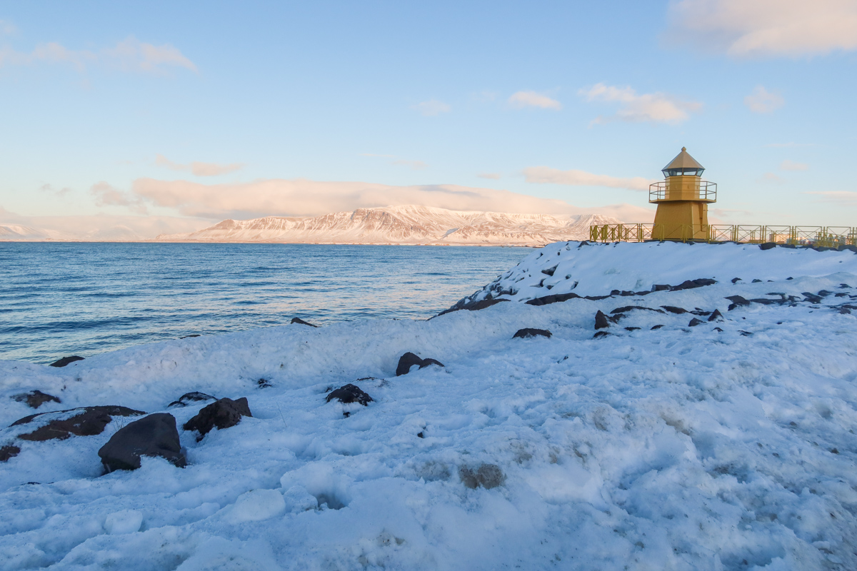 View of the quaint yellow lighthouse on the shore of Reykjavik harbour