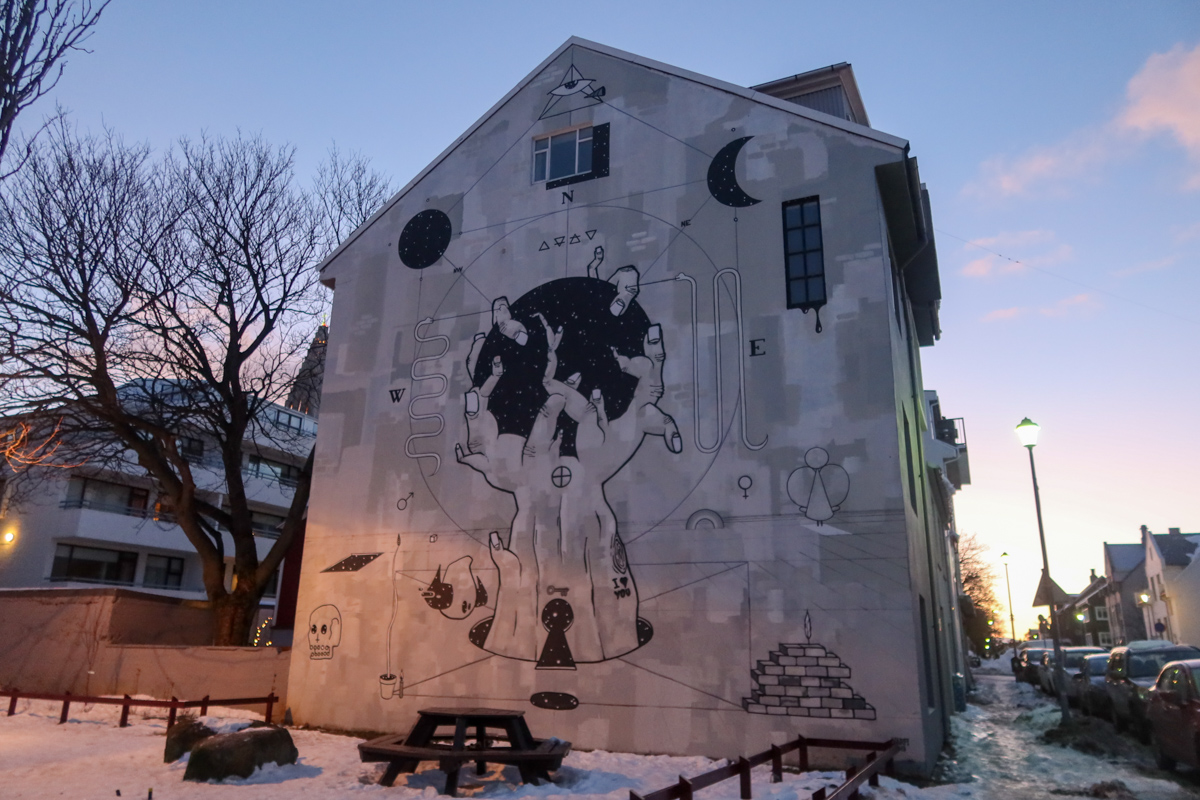 A quirky street art mural showing hands holding a globe in downtown Reykjavik